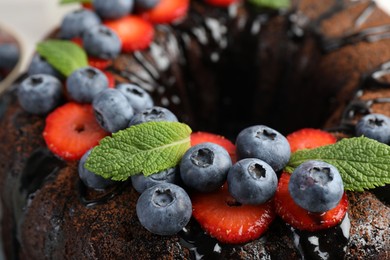 Photo of Delicious chocolate bundt cake with strawberries, mint and blueberries, closeup
