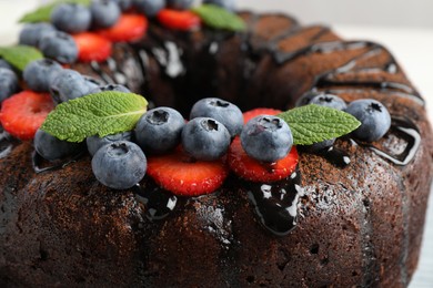 Photo of Delicious chocolate bundt cake with strawberries, mint and blueberries, closeup