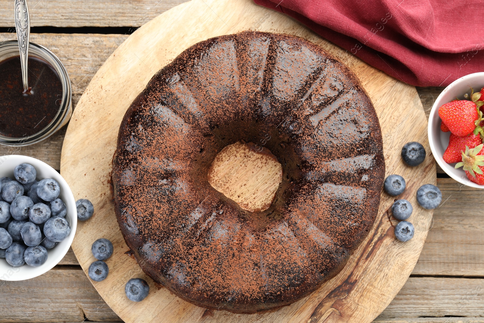 Delicious chocolate bundt cake, strawberries and blueberries on wooden table, flat lay Photo of Delicious chocolate bundt cake, strawberries and blueberries on wooden table, flat lay