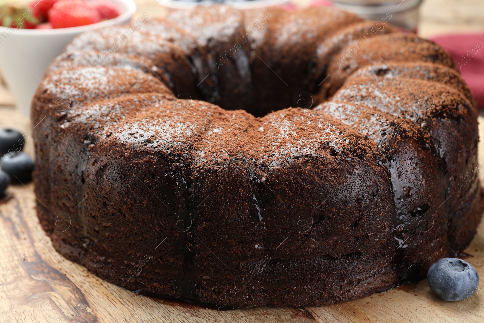 Delicious chocolate bundt cake with blueberries on wooden table, closeup Photo of Delicious chocolate bundt cake with blueberries on wooden table, closeup