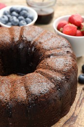 Photo of Delicious chocolate bundt cake on wooden table, closeup