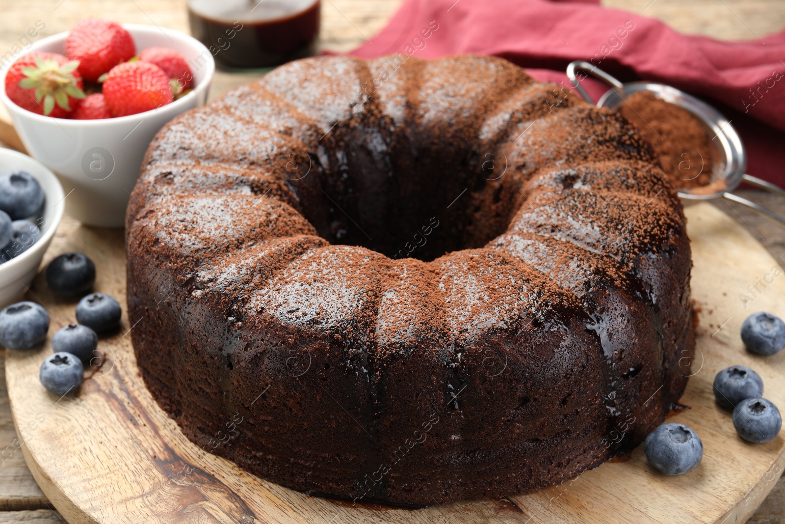 Delicious chocolate bundt cake with blueberries on wooden table, closeup Photo of Delicious chocolate bundt cake with blueberries on wooden table, closeup