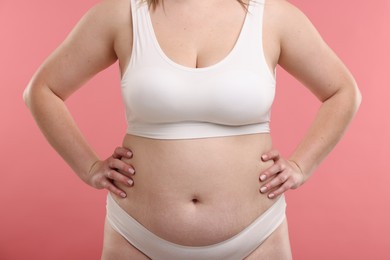 Photo of Weight loss. Plus size woman in underwear on pink background, closeup