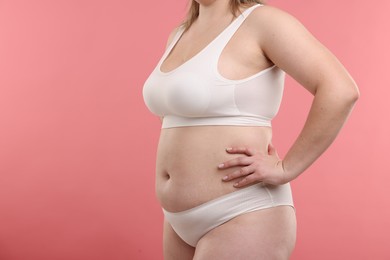 Photo of Weight loss. Plus size woman in underwear on pink background, closeup