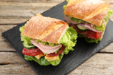 Photo of Tasty baguette sandwich with ham and vegetables on wooden table, closeup