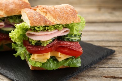Photo of Tasty baguette sandwich with ham and vegetables on wooden table, closeup