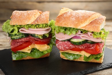 Photo of Tasty baguette sandwich with ham and vegetables on wooden table, closeup