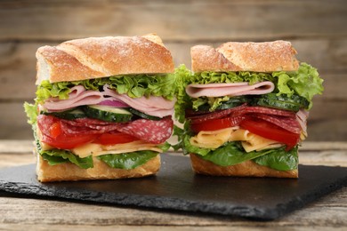 Photo of Tasty baguette sandwich with ham and vegetables on wooden table, closeup