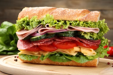 Photo of Tasty baguette sandwich with ham and vegetables on wooden table, closeup