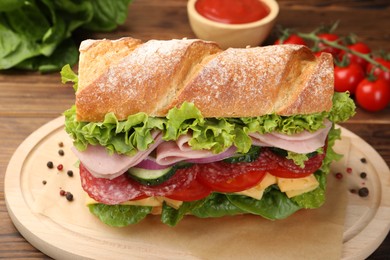 Photo of Tasty baguette sandwich with ham and vegetables on wooden table, closeup