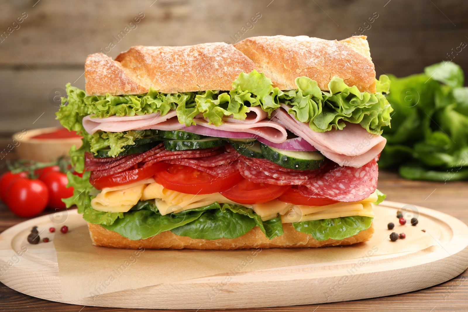 Tasty baguette sandwich with ham and vegetables on wooden table, closeup Photo of Tasty baguette sandwich with ham and vegetables on wooden table, closeup