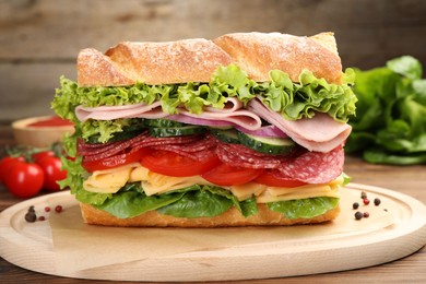 Photo of Tasty baguette sandwich with ham and vegetables on wooden table, closeup