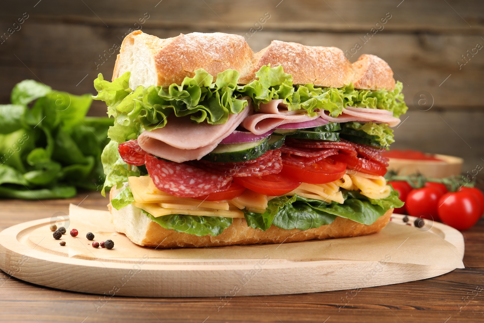 Photo of Tasty baguette sandwich with ham and vegetables on wooden table, closeup