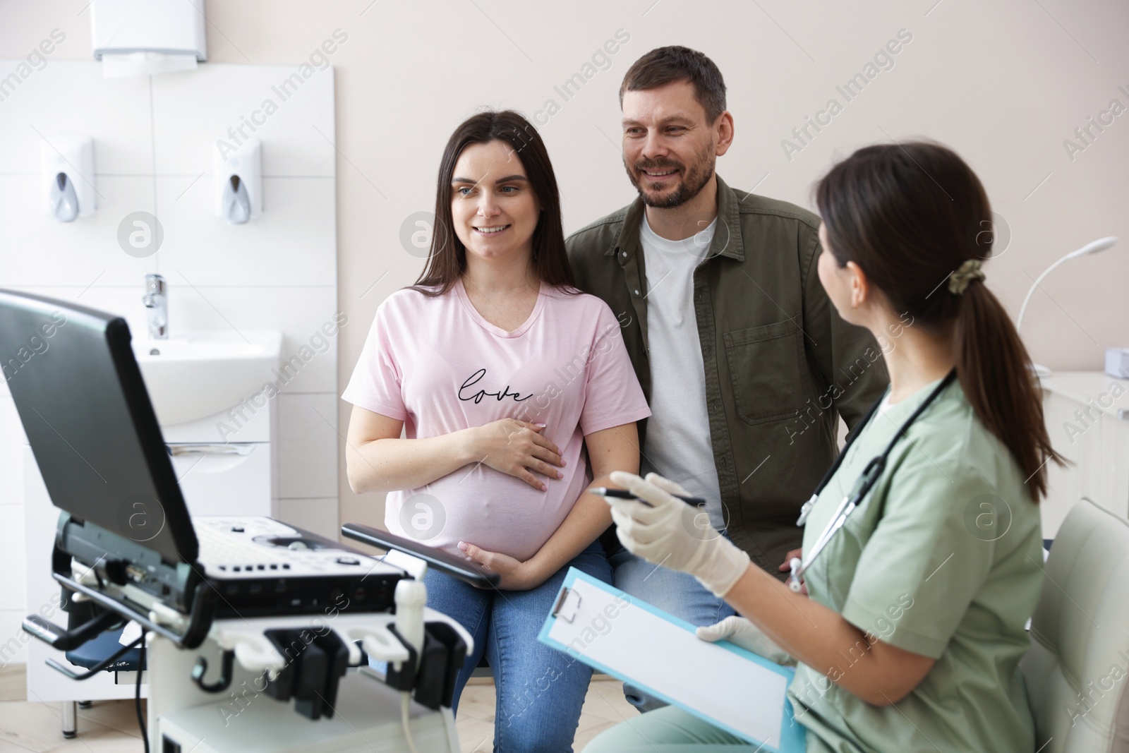 Pregnant couple attending prenatal ultrasound examination in clinic Photo of Pregnant couple attending prenatal ultrasound examination in clinic