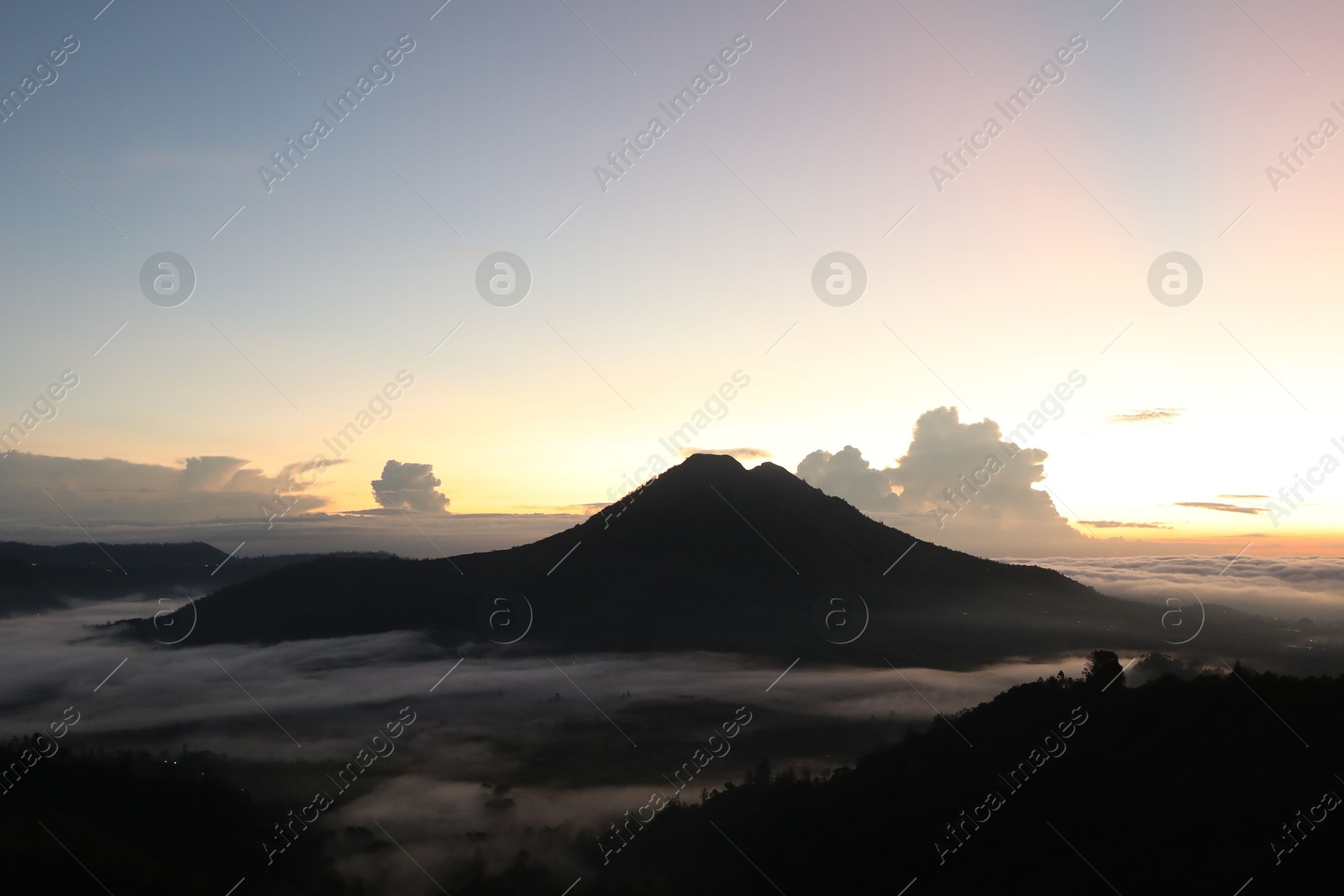 Picturesque view of mountains covered with fog on sunset Photo of Picturesque view of mountains covered with fog on sunset