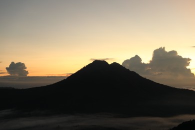 Photo of Picturesque view of mountains covered with fog on sunset