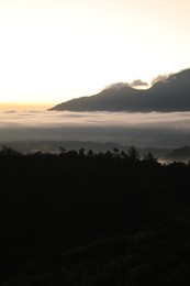 Photo of Picturesque view of mountains covered with fog on sunset