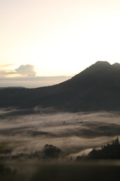 Photo of Picturesque view of mountains covered with fog on sunset