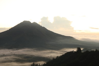 Photo of Picturesque view of mountains covered with fog on sunset