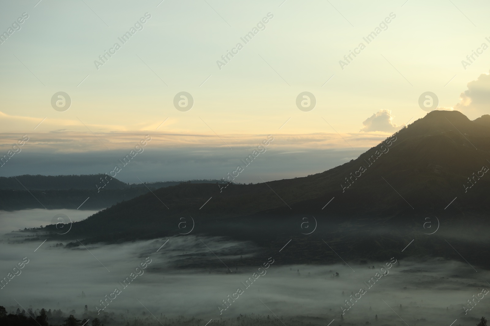 Picturesque view of mountains covered with fog on sunset Photo of Picturesque view of mountains covered with fog on sunset