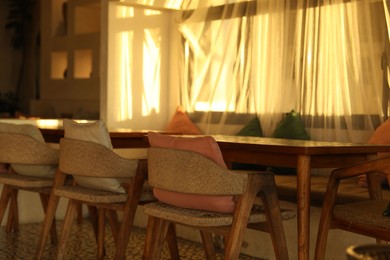 Photo of Wooden table and chairs near window indoors