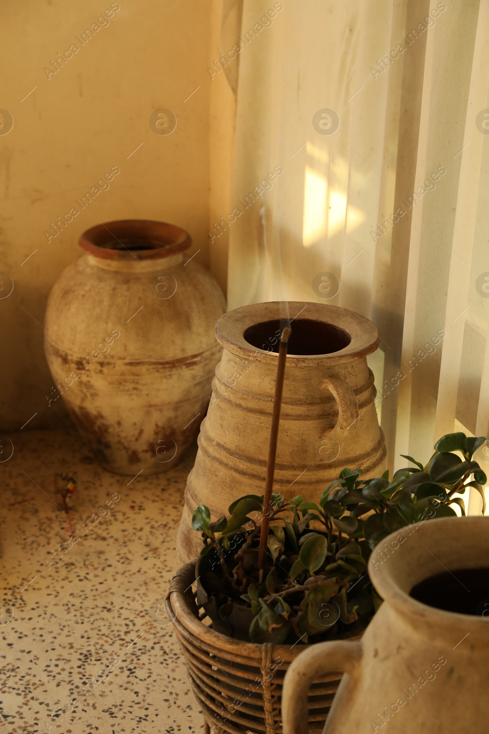 Decorative vases, plant and burning incense indoors Photo of Decorative vases, plant and burning incense indoors