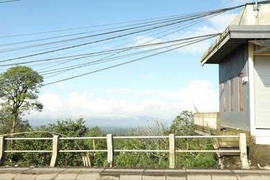 Photo of Electricity wires connecting to building near forest on hill