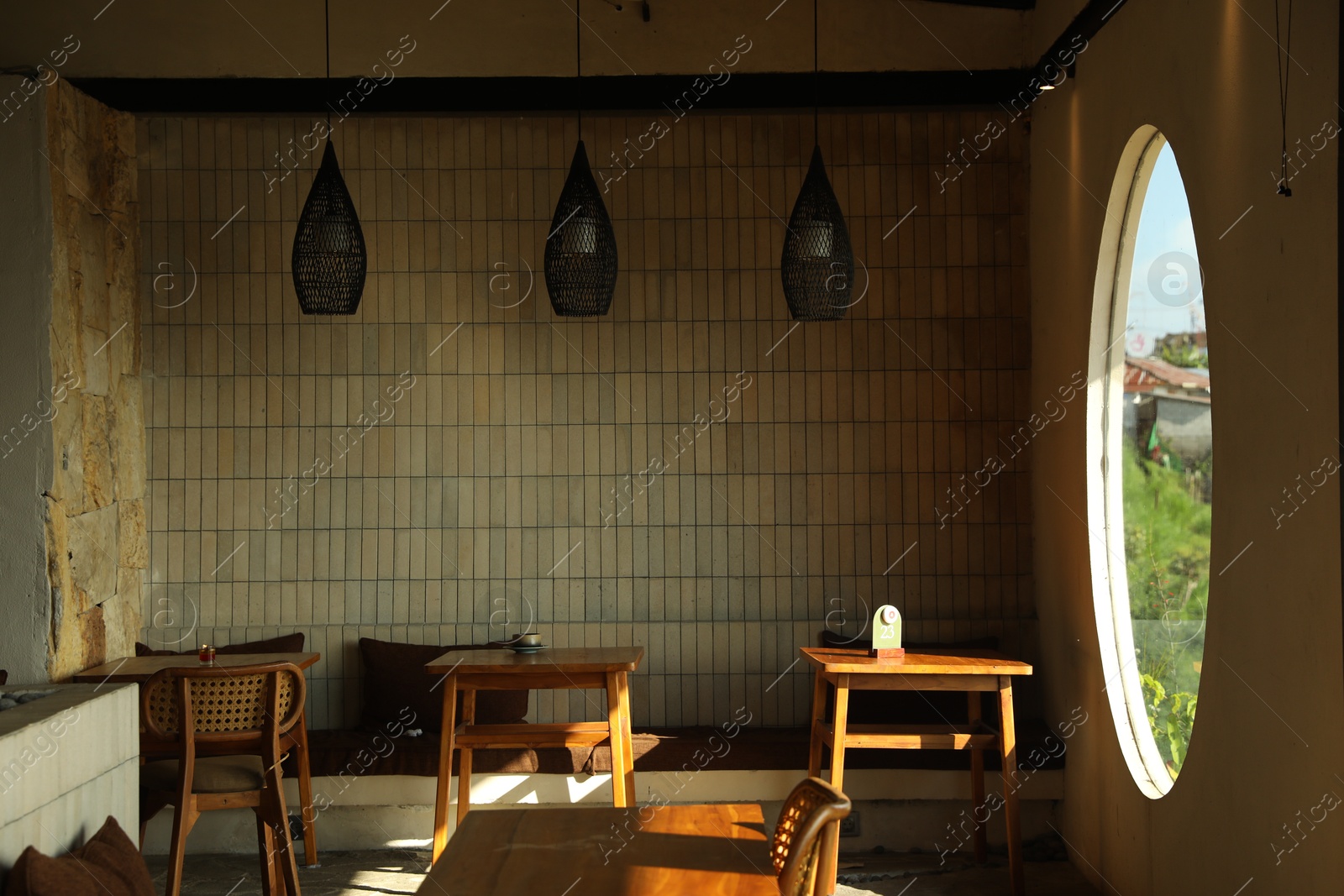 Stylish cafe with wooden furniture and big round window Photo of Stylish cafe with wooden furniture and big round window