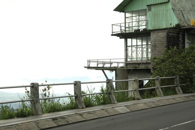 Photo of Safety railing along road and old building. Space for text