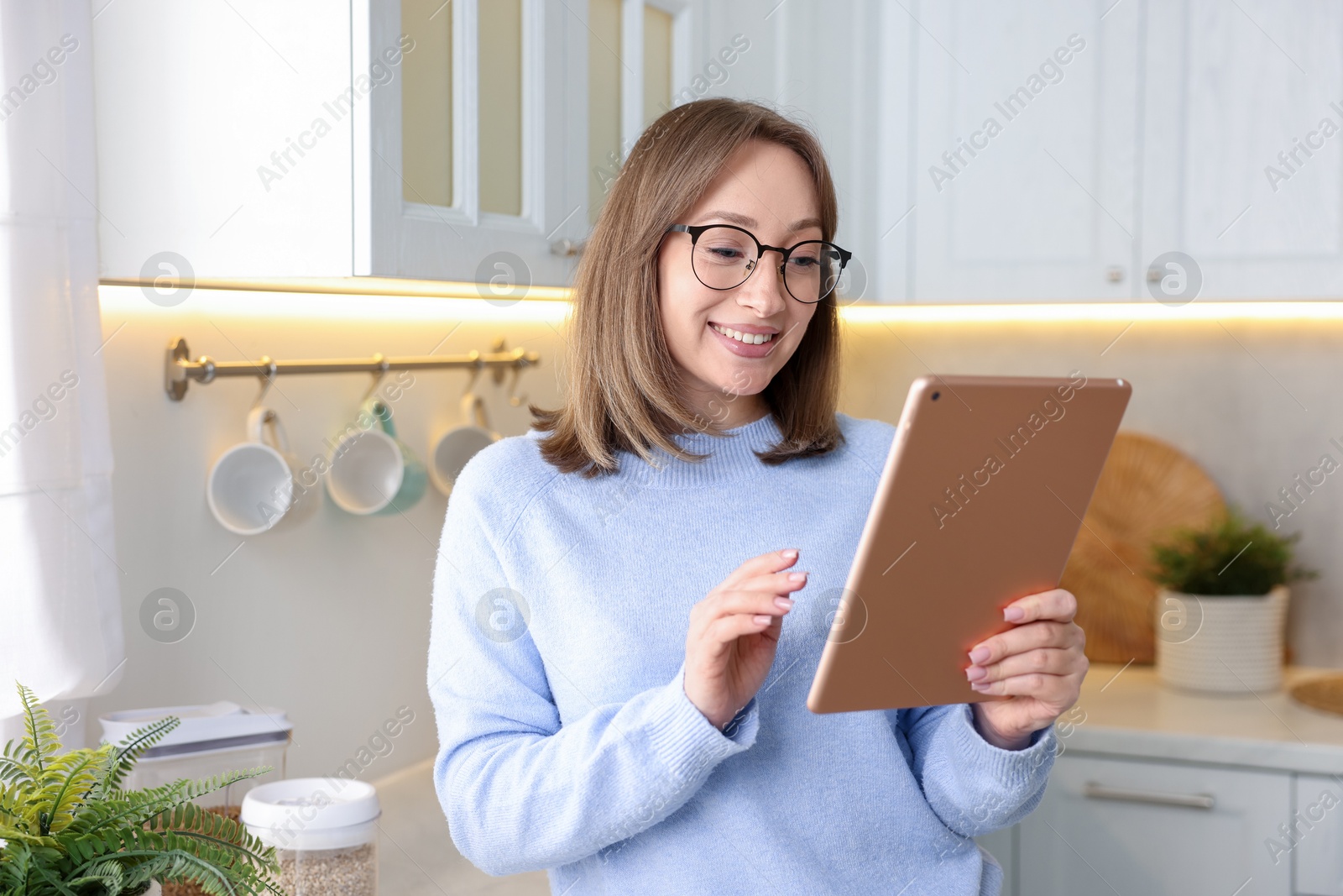 Portrait of woman with modern tablet in kitchen Photo of Portrait of woman with modern tablet in kitchen