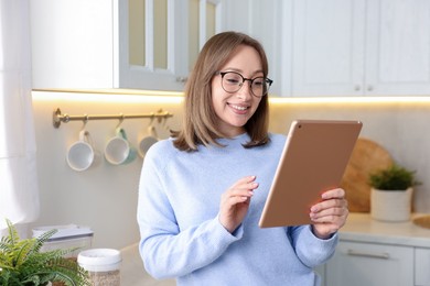 Photo of Portrait of woman with modern tablet in kitchen