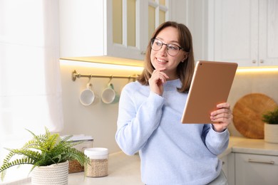 Photo of Portrait of woman with modern tablet in kitchen
