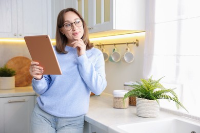 Photo of Portrait of woman with modern tablet in kitchen