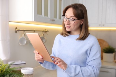 Photo of Portrait of woman with modern tablet in kitchen