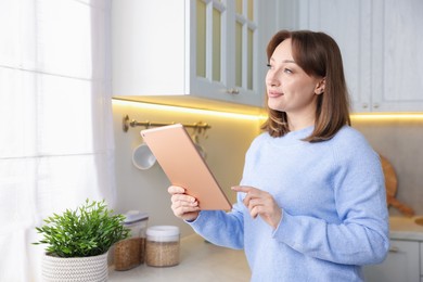 Photo of Portrait of woman with modern tablet in kitchen