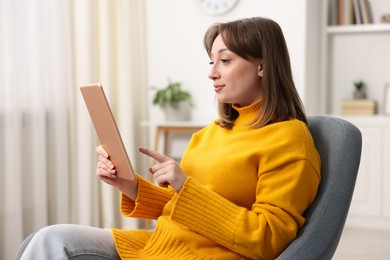 Photo of Woman with modern tablet in armchair at home