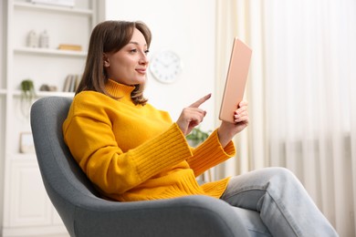 Photo of Woman with modern tablet in armchair at home