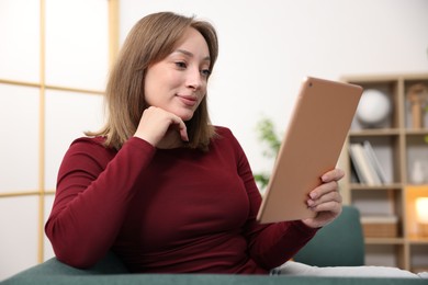 Photo of Woman with modern tablet on sofa at home