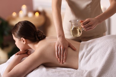 Photo of Woman receiving back massage with oil in spa salon