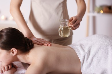 Photo of Woman receiving back massage with oil in spa salon, closeup