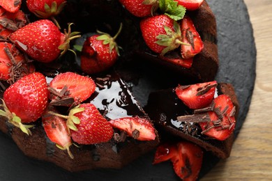 Photo of Delicious bundt cake with strawberries and chocolate shavings on wooden table, top view