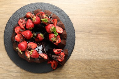 Photo of Delicious bundt cake with strawberries and chocolate shavings on wooden table, top view. Space for text