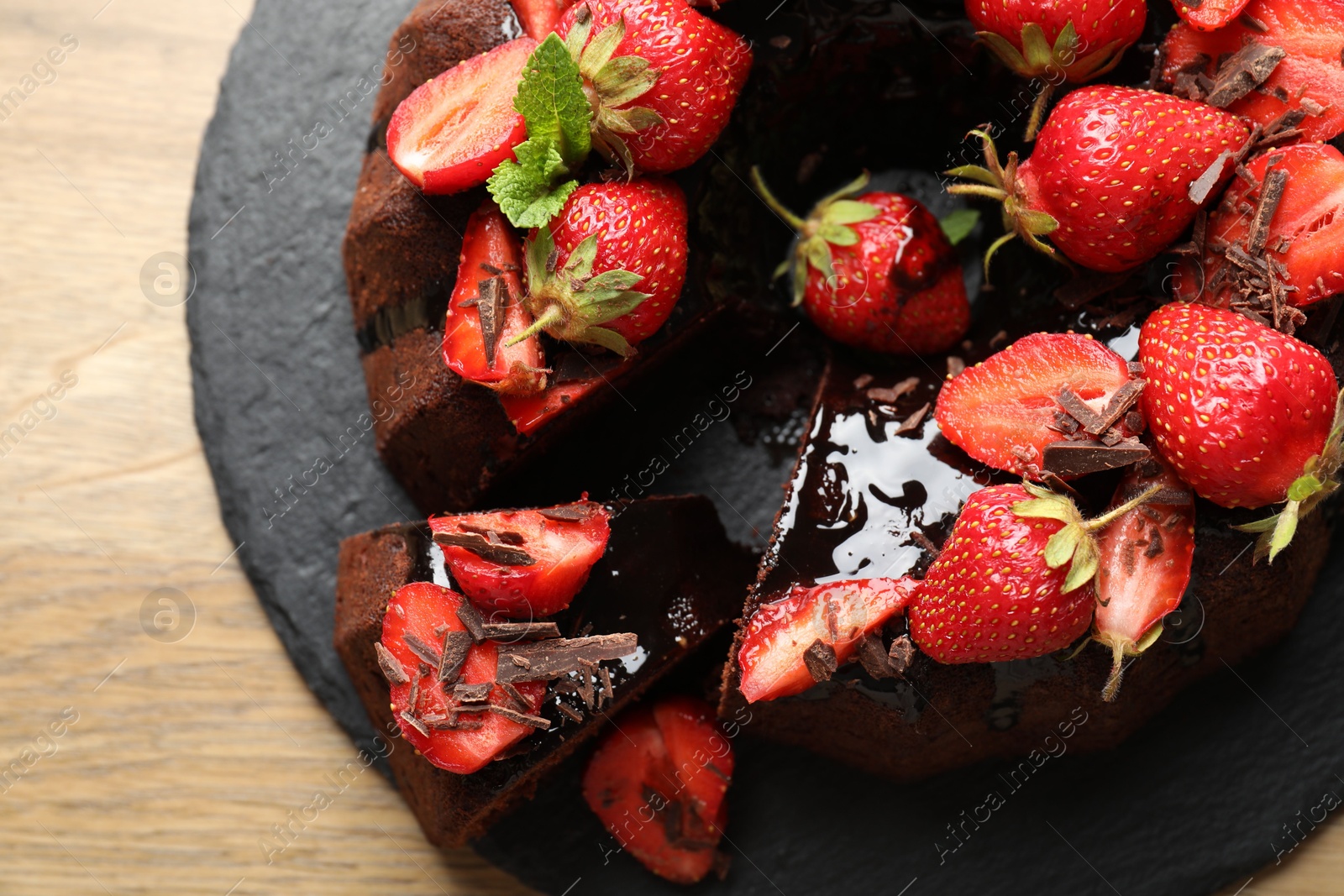Delicious bundt cake with strawberries and chocolate shavings on wooden table, top view Photo of Delicious bundt cake with strawberries and chocolate shavings on wooden table, top view