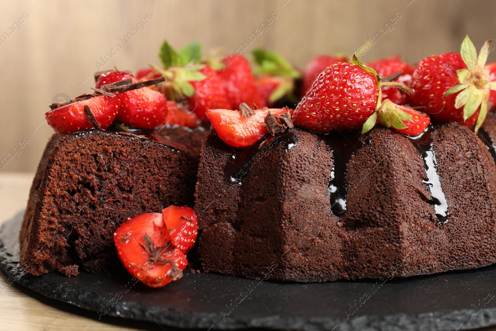 Delicious chocolate bundt cake with strawberries on wooden table, closeup Photo of Delicious chocolate bundt cake with strawberries on wooden table, closeup