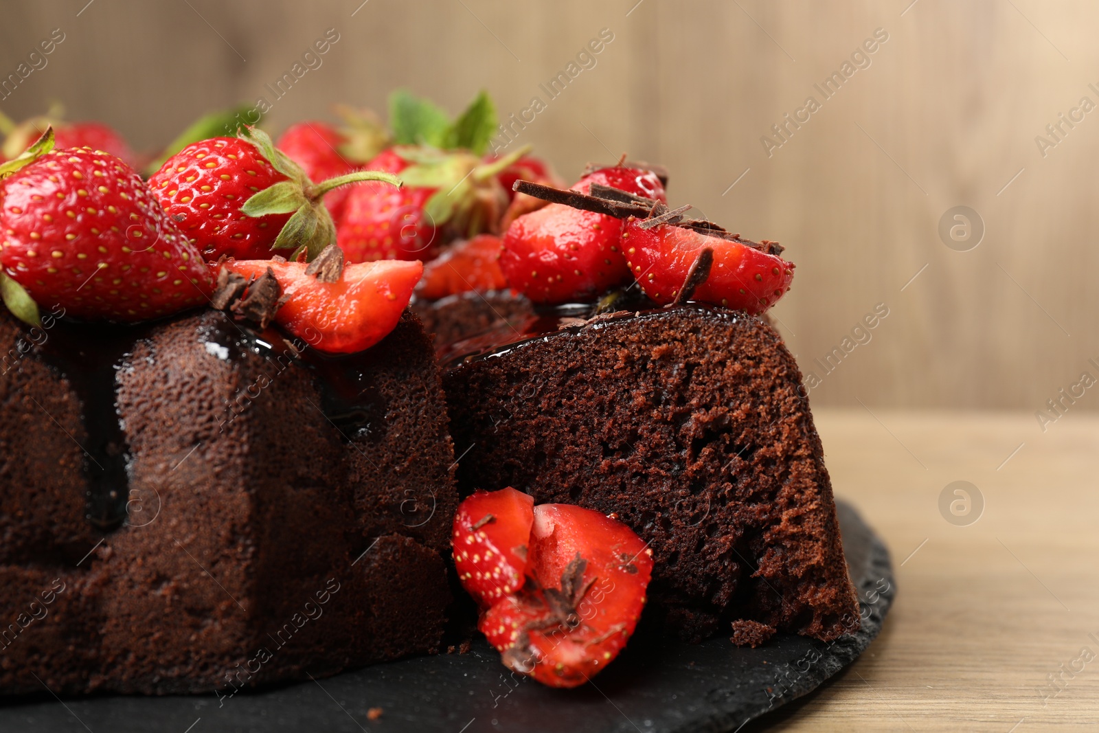 Delicious chocolate bundt cake with strawberries on wooden table, closeup Photo of Delicious chocolate bundt cake with strawberries on wooden table, closeup
