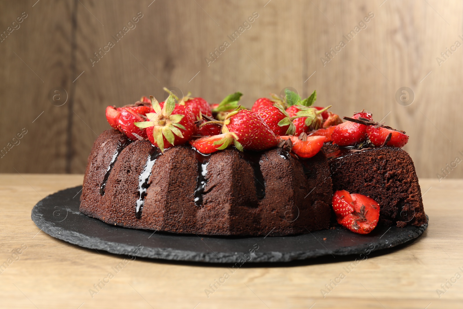 Delicious chocolate bundt cake with strawberries on wooden table, closeup Photo of Delicious chocolate bundt cake with strawberries on wooden table, closeup
