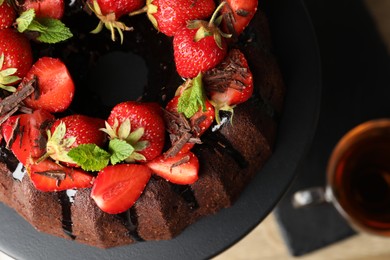 Photo of Delicious bundt cake with strawberries and chocolate shavings on table, top view
