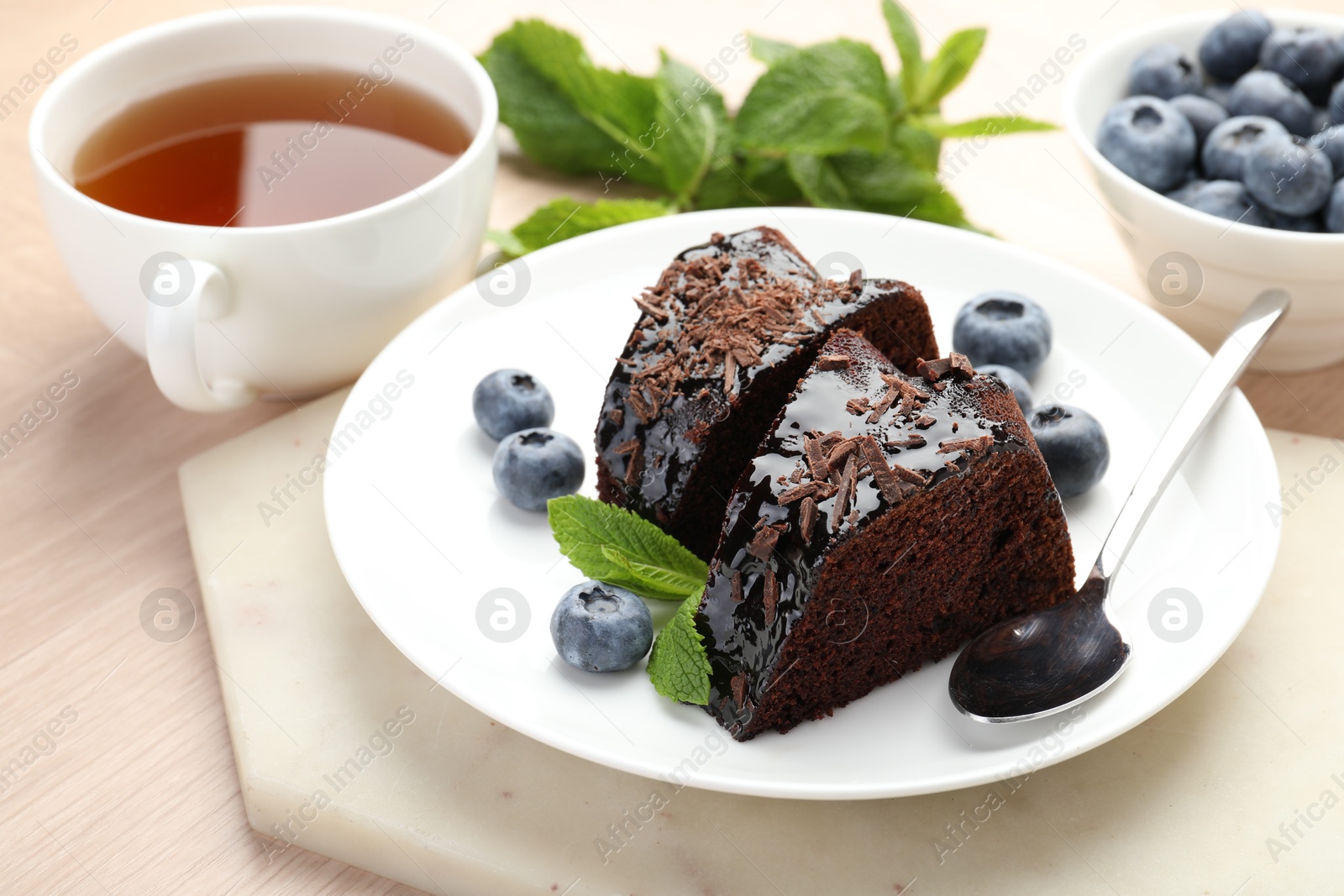 Pieces of delicious bundt cake with blueberries, mint, chocolate shavings and tea on wooden table, closeup Photo of Pieces of delicious bundt cake with blueberries, mint, chocolate shavings and tea on wooden table, closeup