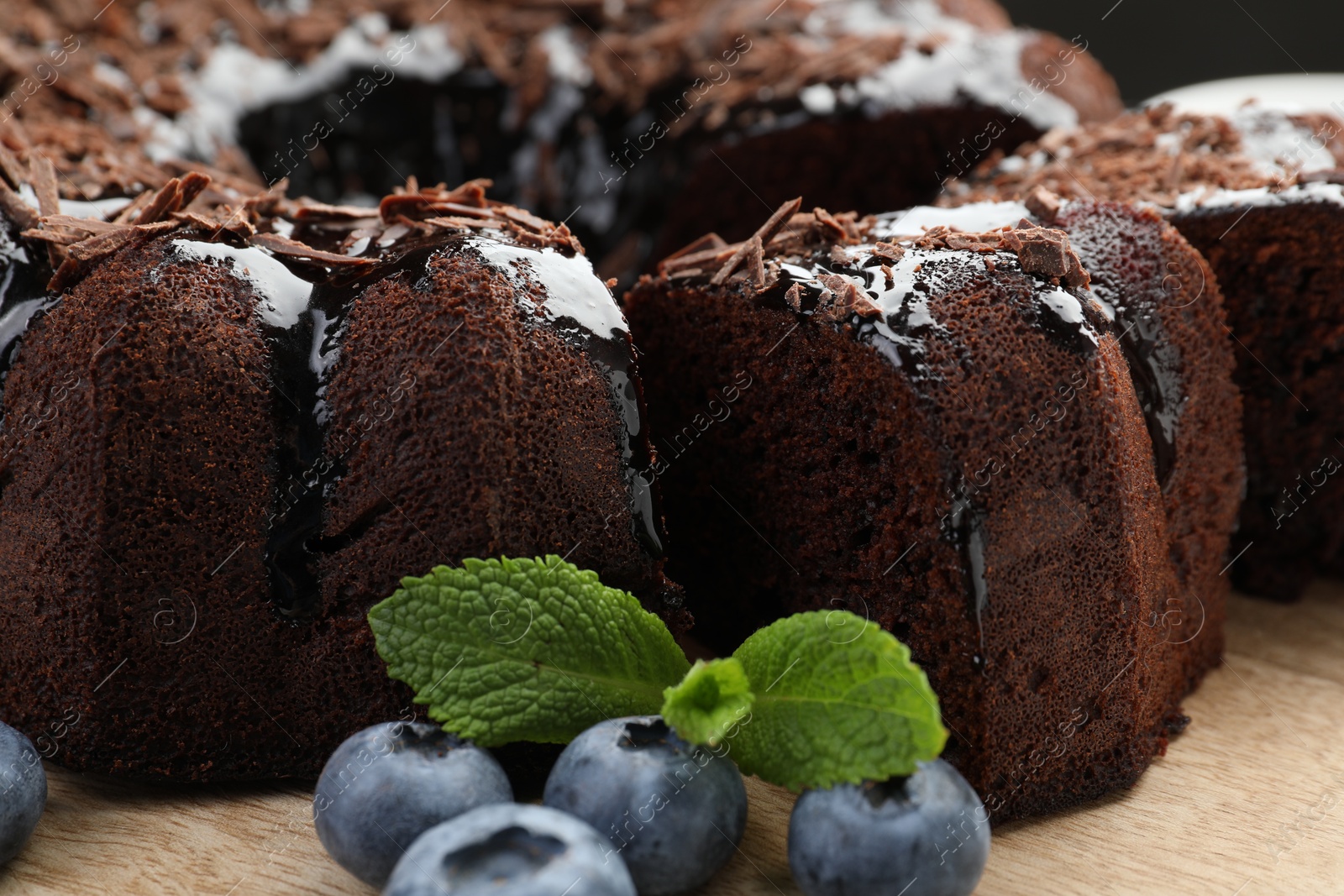 Delicious bundt cake with blueberries, mint and chocolate shavings on wooden table, closeup Photo of Delicious bundt cake with blueberries, mint and chocolate shavings on wooden table, closeup