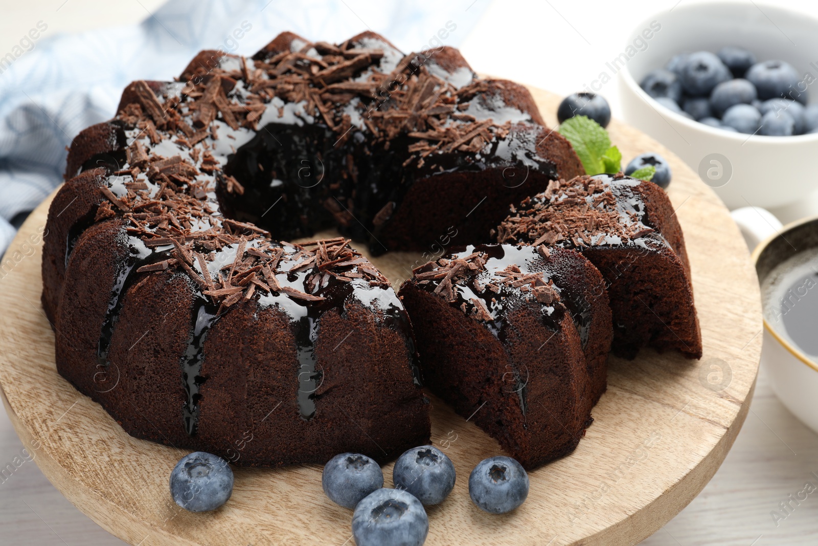 Delicious bundt cake with blueberries and chocolate shavings on light wooden table, closeup Photo of Delicious bundt cake with blueberries and chocolate shavings on light wooden table, closeup